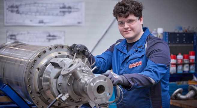 Mitarbeiter bzw. Auszubildender von FILTRATEC in Schutzkleidung arbeitet an einer industriellen Filterkomponente in einer Werkstattumgebung.