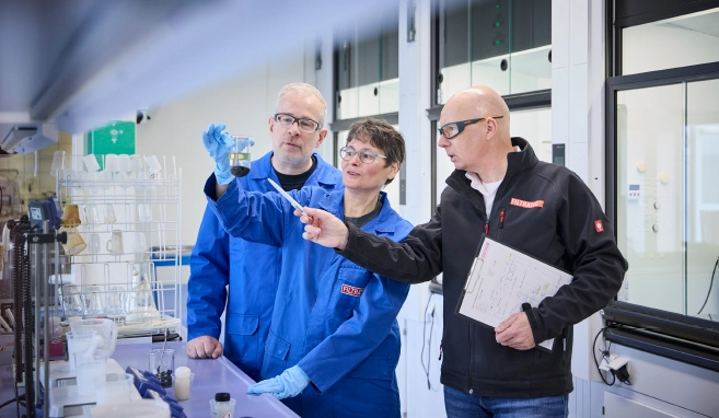 Drei Mitarbeitende von FILTRATEC analysieren gemeinsam eine Flüssigkeitsprobe im Labor und besprechen die Ergebnisse.