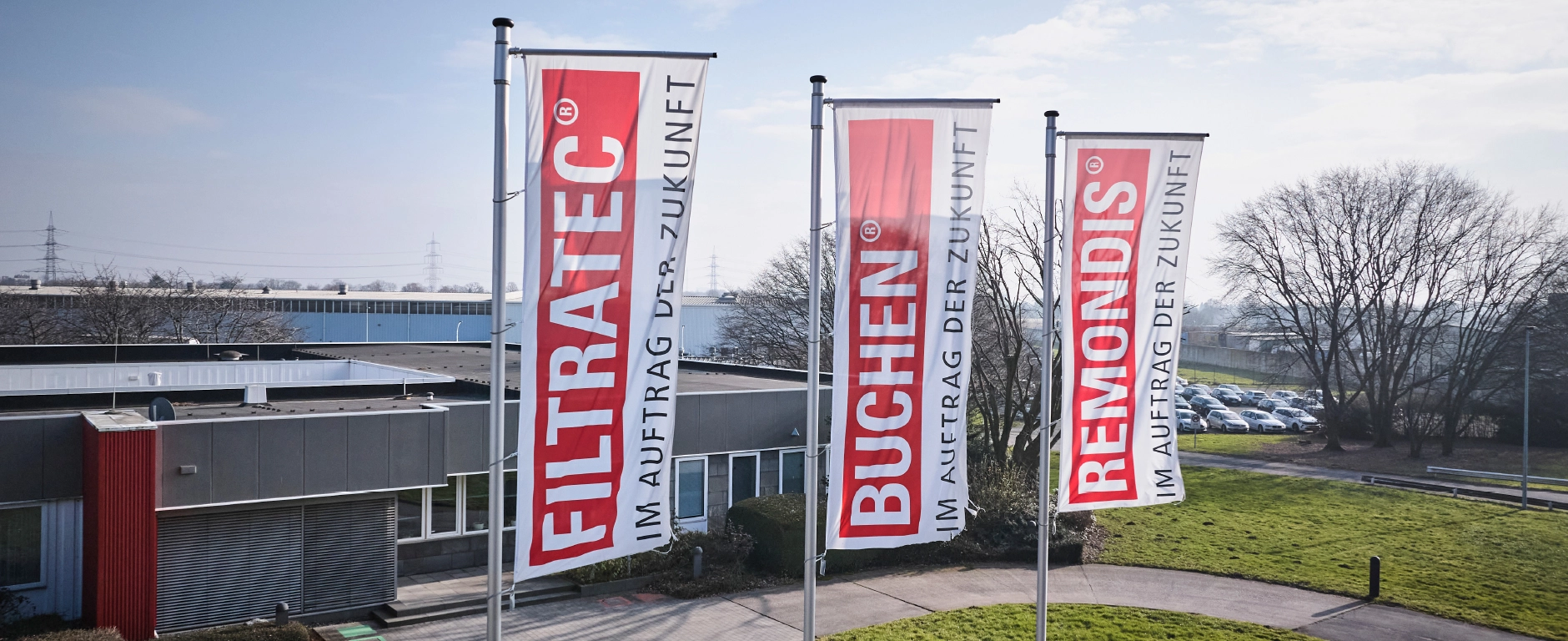 Firmengebäude mit drei Fahnen FILTRATEC, BUCHEN und REMONDIS sowie dem Slogan „Im Auftrag der Zukunft“ auf dem Betriebsgelände.
